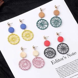 Detail view of four pairs of bohemian wooden weave earrings on white display paper