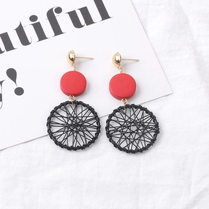 Flat lay of long red and black geometric earrings on fabric with a decorative card