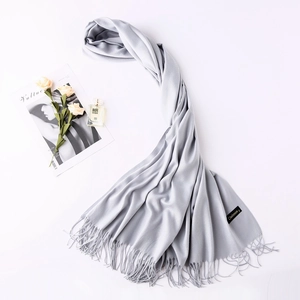 Close-up of a light grey cashmere scarf showing soft texture and premium fringe details