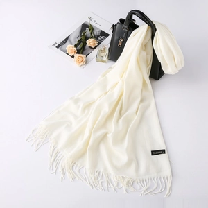 Cream cashmere wool scarf with fringe detail styled with fashion accessories on a white surface