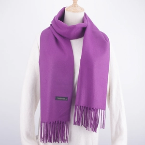 Detailed view of purple cashmere wool scarf texture with fringe tassels and woven brand label