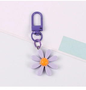 Close-up of a purple daisy keychain pendant with orange stamen and metal clasp hook