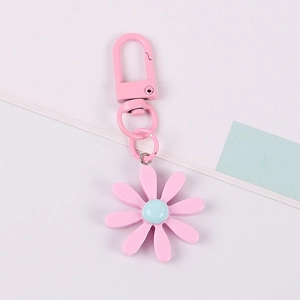 Pink daisy flower keychain with blue center and pink metal hook on white background
