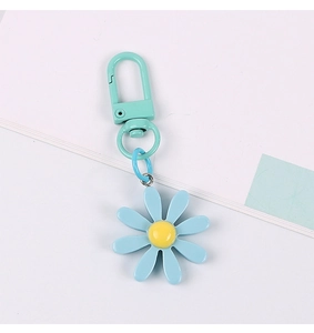 Detailed view of a blue daisy flower keychain with matching D-ring on a laptop