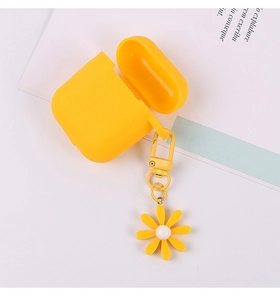 Top view of yellow silicone AirPods case with daisy charm and carabiner on white desk