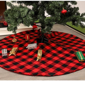 Detail of red and black buffalo plaid Christmas tree skirt in a cozy fireplace setting