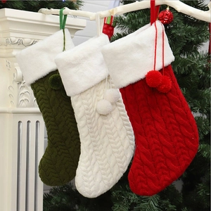 Trois chaussettes de Noël tricotées en rouge blanc et vert suspendues près d'une cheminée