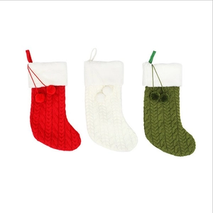 Trois chaussettes de Noël en tricot rouge, blanc et vert avec revers en peluche et pompons