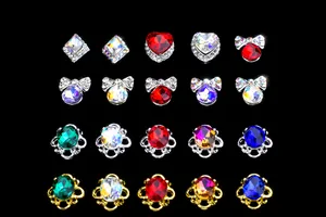 Vue macro de breloques à ongles cœurs et nœuds avec cristaux colorés et base dorée
