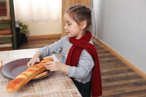 Detail of red knit scarf on child model, showing soft warm ribbed texture and fabric