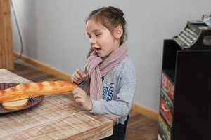 Detailed knit texture of pink winter scarf worn by a child in a cozy indoor setting
