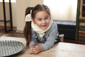 Detail of child wearing a cream knit warm winter scarf with Tiger patterned gray sweater