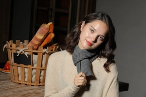 Close-up of gray ribbed knit scarf texture worn by model in cozy kitchen setting