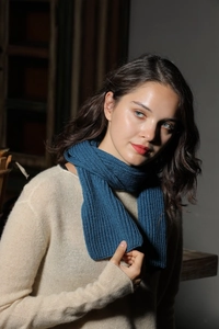 Detail of soft blue knitted ribbed scarf texture worn with a beige sweater