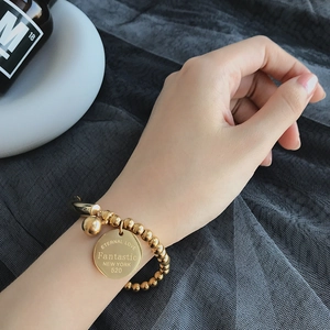 Detail of gold beaded titanium steel bracelet featuring engraved eternal love charm on wrist