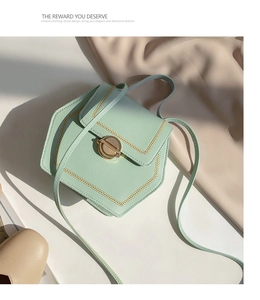 Detail of mint green geometric bag with contrast stitching and golden turn-lock closure