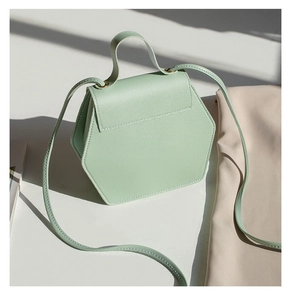 Detail view of a mint green hexagonal leather crossbody bag with top handle and hard shadows