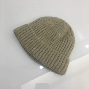 Detailed view of the ribbed knit texture on a light beige rolled edge beanie hat