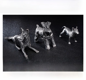 Detailed view of three stainless steel dog figurines with fine fur texture on black background