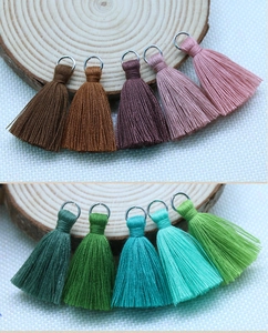 Macro view of 10 assorted colors DIY cotton tassels with silver metal rings on wood