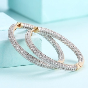 Sparkling gold hoop earrings with pavé cubic zirconia on a light blue jewelry box