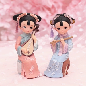 Detail of pink and blue resin dolls playing instruments with soft floral background