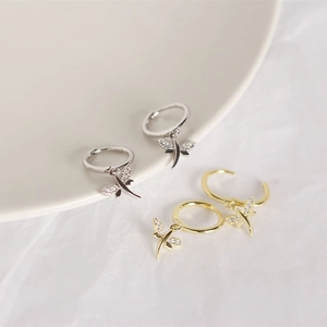 Macro detail of silver and gold dragonfly hoop earrings with cubic zirconia on white tray