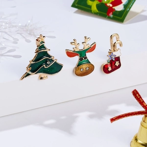 Detail of Christmas enamel brooch set with tree and reindeer on a white minimalist stage