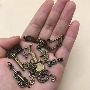 Antique bronze music pendants including guitar and violin charms held in hand for scale