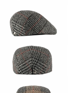 Close-up of wool flat cap showing gray red plaid tweed texture and metal button detail