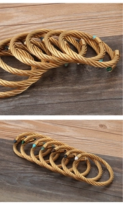 Detail of gold twisted cable bracelets with colorful tapered gemstone tips on wood