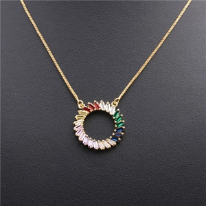 Close-up of golden necklace featuring a round pendant with colorful rainbow zircons