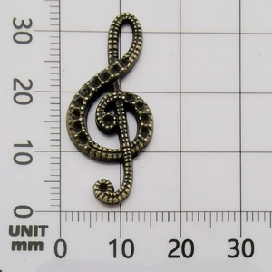 Antique bronze music note G-clef pendant on measurement grid showing 31mm height