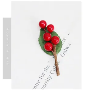 Dettaglio di bacche rosse artificiali con foglia verde per decorazioni fai da te