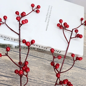 Artificial red berry stems on a book and wooden table for Christmas floral decor