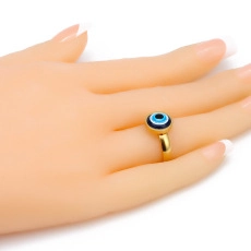 Close-up of golden Evil Eye ring with blue enamel inlay worn on a hand over white background