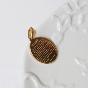 Close-up of golden oval stainless steel pendant with Spanish driver prayer engraving