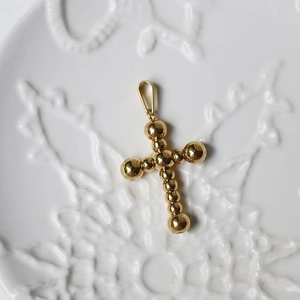 Detail of 18K gold-plated titanium steel cross pendant with spherical elements on ceramic