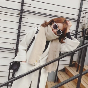 Détail d'une écharpe en maille beige montrant l'étiquette et la texture sur un mannequin