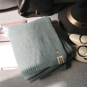 Détail d'une écharpe en maille vert clair avec broderie ananas et étiquette tissée