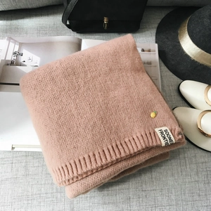Détail de l'écharpe en maille rose avec texture côtelée, badge ananas et étiquette