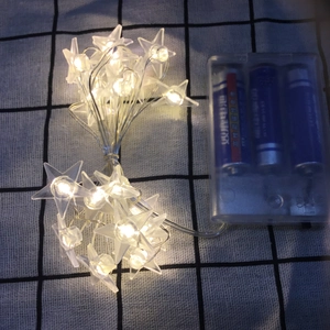 Close-up of star-shaped LED fairy lights with clear battery box and warm white glow