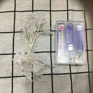 Star-shaped LED fairy lights with battery box and three AA batteries on a checkered cloth