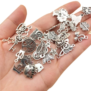 Assorted silver alloy charms in hand including hearts, keys, and animal shapes for DIY jewelry