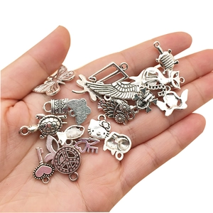 Detailed close-up of mixed antique silver alloy pendants in various shapes held in hand