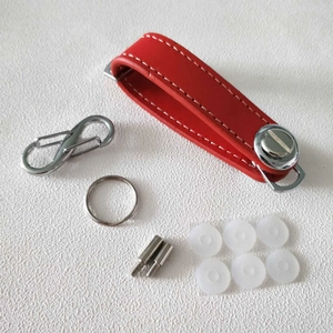 Flat lay of red PU leather key organizer strap with metal screws and accessories set