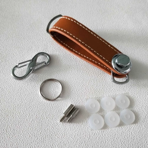 Brown leather key organizer set with metal screw posts and quick release clip on textured table