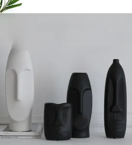 Close-up of matte white and black ceramic vases with Nordic abstract face design