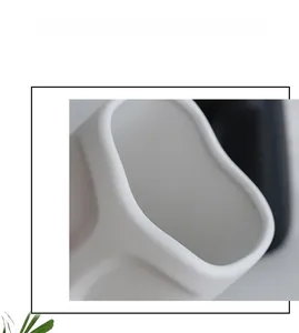 Close-up of matte white ceramic vase showing irregular curved rim and smooth frosted texture
