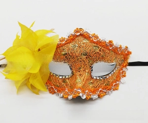 Close-up of orange lace masquerade mask with golden glitter and yellow side flower